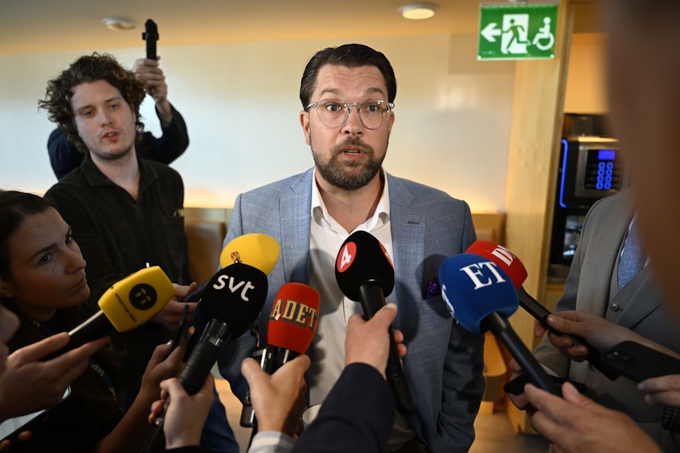 Sverigedemokraternas partiledare Jimmie Åkesson pratar inför flera reportrar i riksdagen.