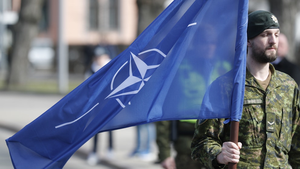 En lettisk serviceman med Nato-flaggan vid ett jubileum.