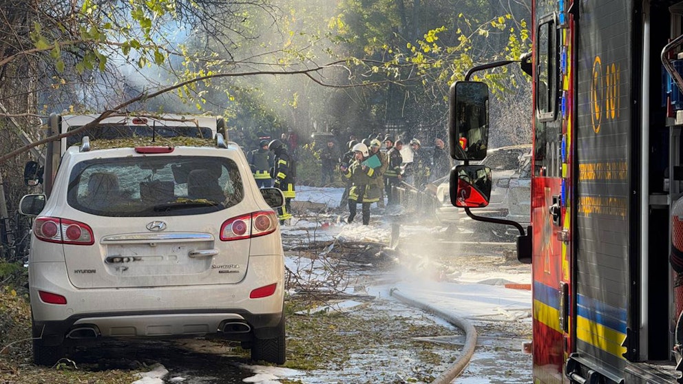 Solljus i ett bostadsområde i Odessa, vatten och skum från brandsläckare på marken, räddningspersonal går runt på gräset