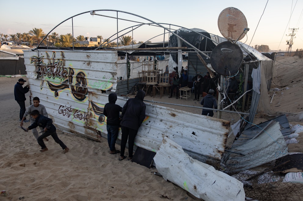 Människor i och omkring ett förstört café på sand i Gaza.