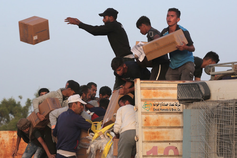En grupp människor trängs vid en lastbil och plockar kartonger från den.