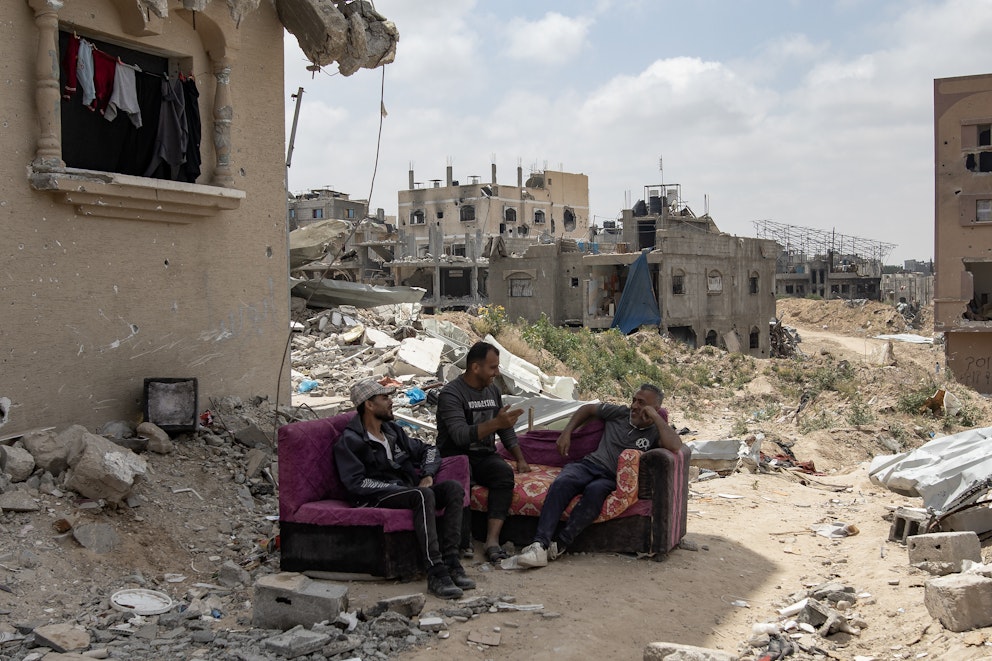 Tre män sitter på en soffa invid ruinerna av sitt förstörda hem i Khan Yunis efter att den israeliska armén dragit tillbaka sina styrkor från södra Gazaremsan.