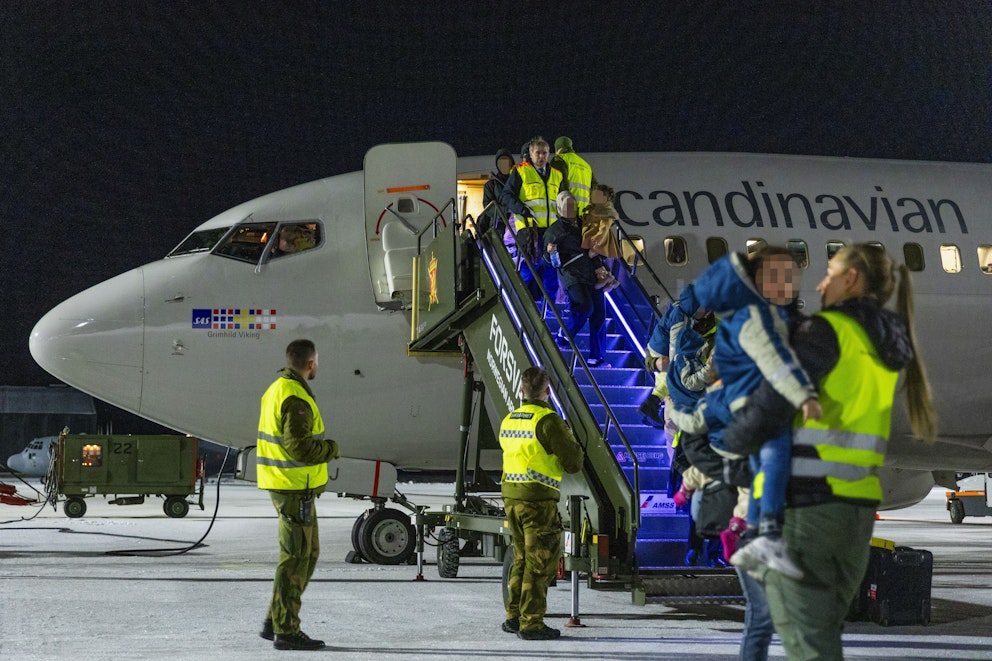 Flygplatspersonal med reflexvästar möter barnen från Gaza och deras anhöriga när de går ned från ett flygplan på flygplatsen.