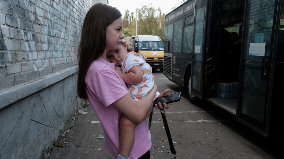 Mamma med sitt barn väntar på att evakueringsbussen ska avgå från Pokrovsk. 