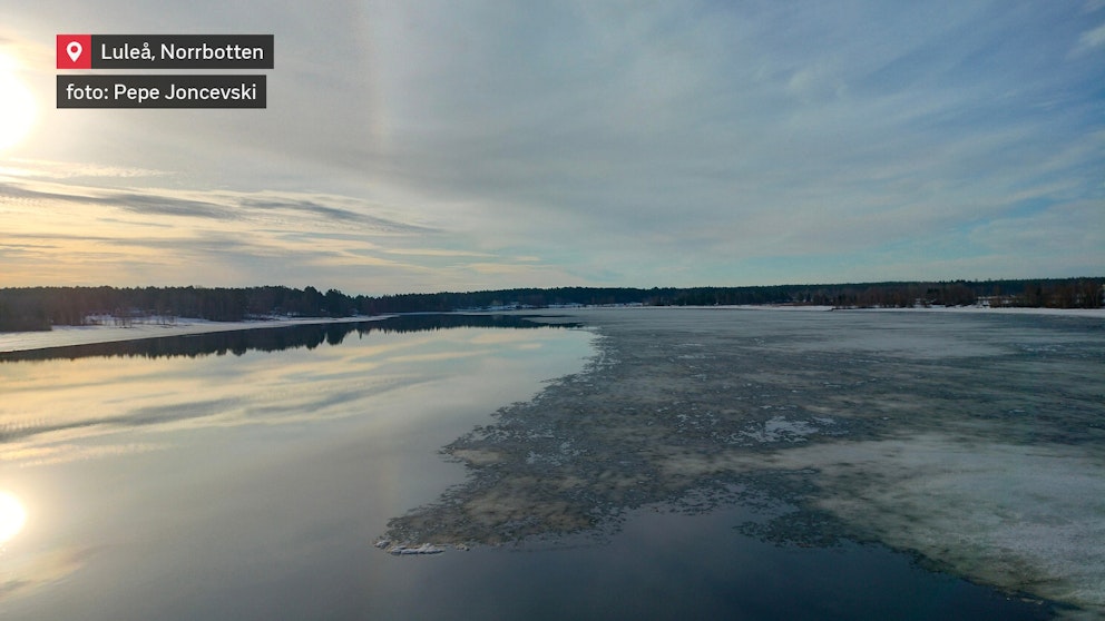 Isen smälter på Luleälv. Halva även är på bilden täckt med is medan den andra halvan ligger öppen. På himlen syns en liten bit halo nära solen.
