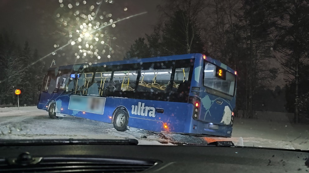 blås buss som står lutande, halvvägs av vägen nära en korsning, snö