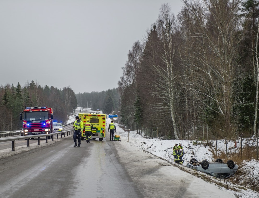 bil upp och ned i diket, brandbil och ambulans på vägen