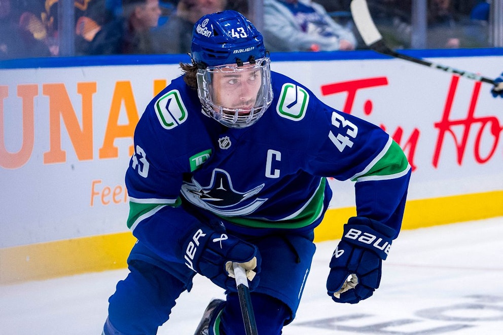 Ihockeyspelaren Quinn Hughes under en NHL-match iförd Vancouver Canucks blåa ställ. Här i heltäckande visir för ansiktet.