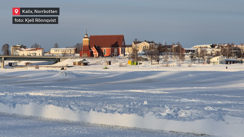 Vintersolen lyser över Kalix och den frusna älven, där skidspår och isvägar slingrar sig fram. I bakgrunden reser sig den ståtliga kyrkan, en välkänd siluett i det snöklädda landskapet. En stillsam vinterdag i Norrbotten.