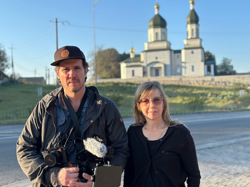 Fotograf Lars Lyrefelt och Elin Jönsson framför en vit kyrka