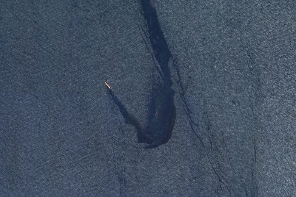 Satellitbild på ett fartyg med en tjock sträng av mörk olja bakom sig.