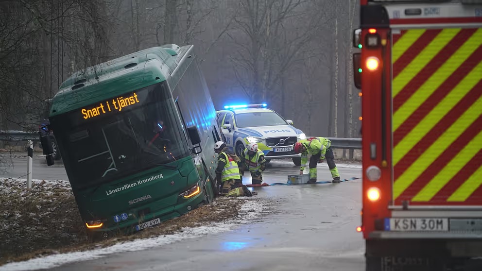 Buss som står i diket. Polisbild och brandbil står i närheten, räddningstjänsten arbetar med att få loss bussen.