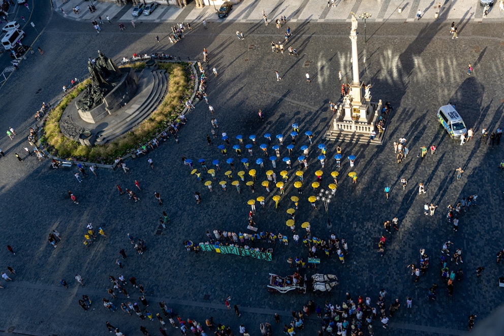 Personer i Tjeckiens huvudstad bildar en ukrainsk flagga av blå och gula paraplyer. Foto: Martin Divsek/EPA/TT