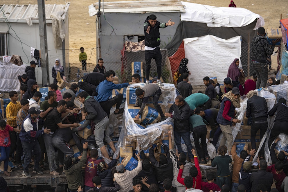 Människor sliter i lådor med humanitärt stöd på en lastbil.