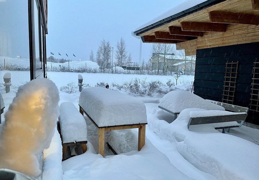snötäckta bänkar och en skottad gång i snödrivor mellan två byggnader