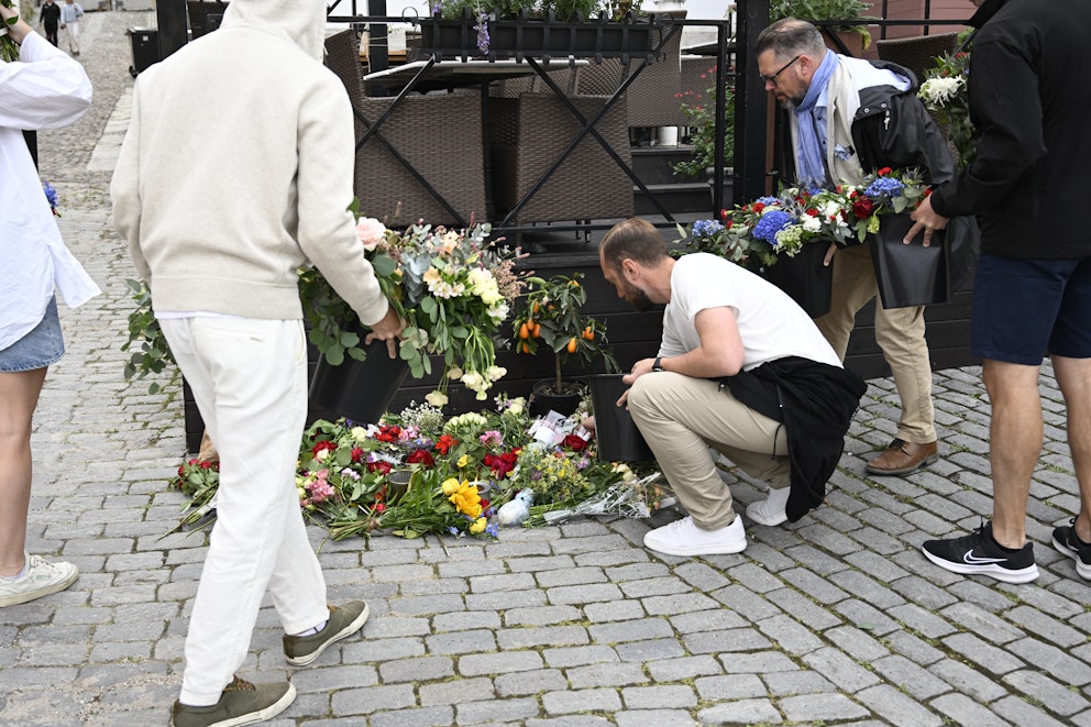 Personer lägger ned blommor vid Donners plats i Visby.