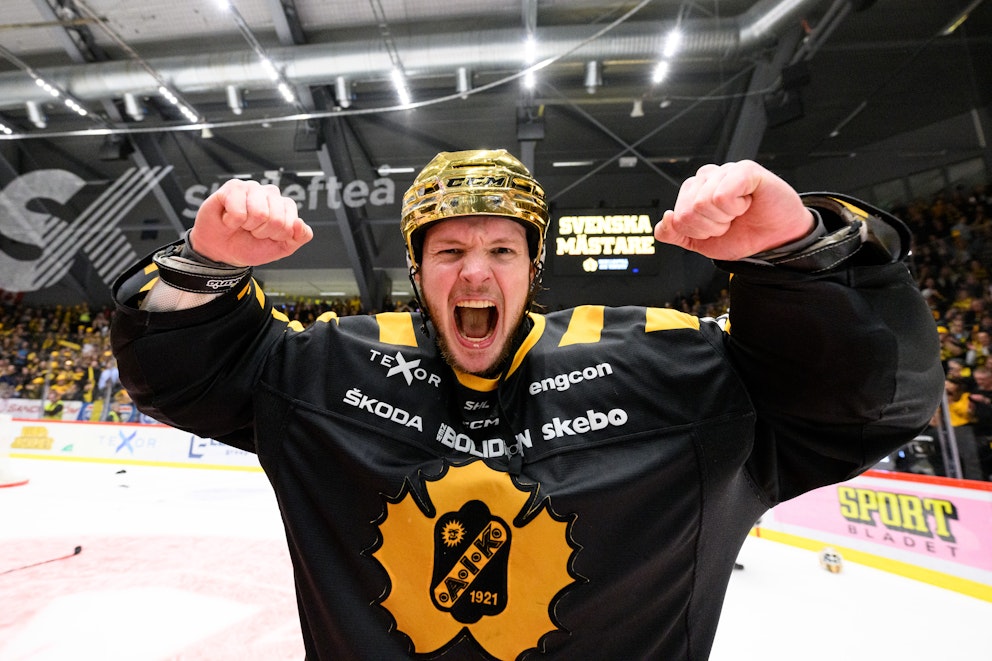 En jublande ishockeyspelare med guldhjälm.