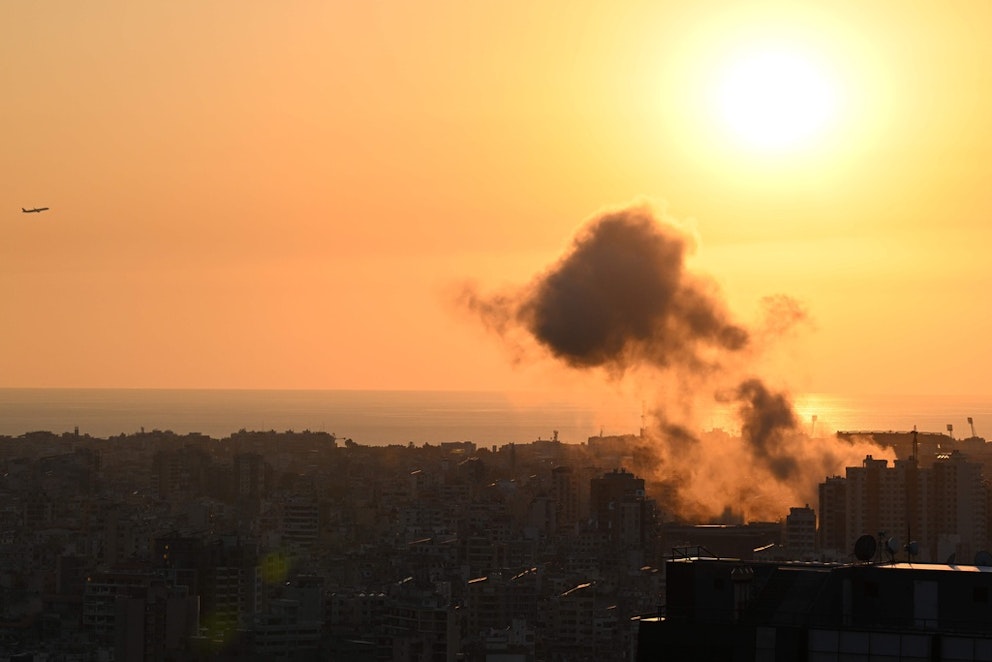 Rök stiger från himlen efter en israelisk attack mot Shiyah i södra Libanon under lördagen. På himlen syns även ett flygplan. Foto: Joseph Eid/AFP/TT