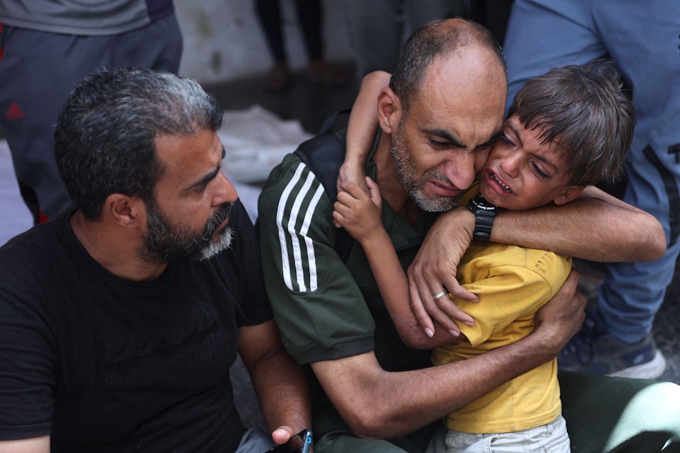 Ett palestinskt barn tröstas av en vuxen efter en israelisk bombning i Gaza den 4 juli.